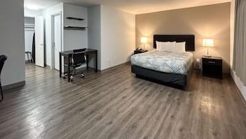 Una habitación de hotel con cama, mesitas de noche, un escritorio y una silla.