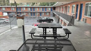 Um terraço no telhado com mesa de piquenique e churrasqueira de metal.