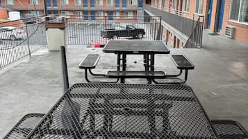 Un patio en la azotea con una mesa de picnic y una parrilla de metal.