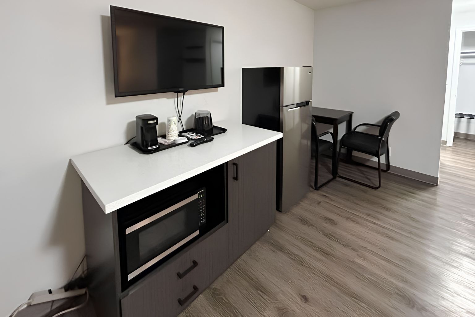 Una cocina moderna con televisor de pantalla plana, cafetera y refrigerador.