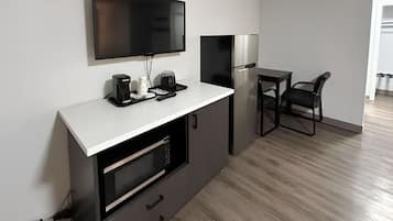 Una cocina moderna con televisor de pantalla plana, cafetera y refrigerador.