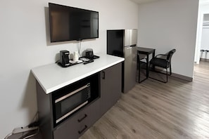 Eine moderne Küche mit Flachbildfernseher, Kaffeemaschine und Kühlschrank.