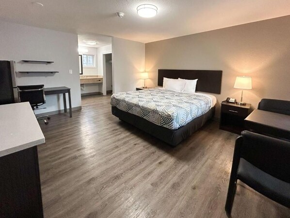 Ein Hotelzimmer mit Bett, Schreibtisch, Stuhl und einer kleinen Küchenzeile.