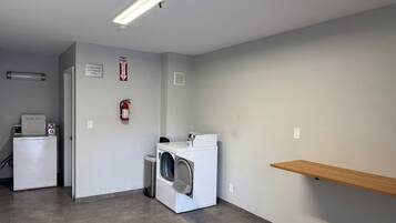 A laundry room with a washing machine, dryer, and a fire extinguisher on the wall.