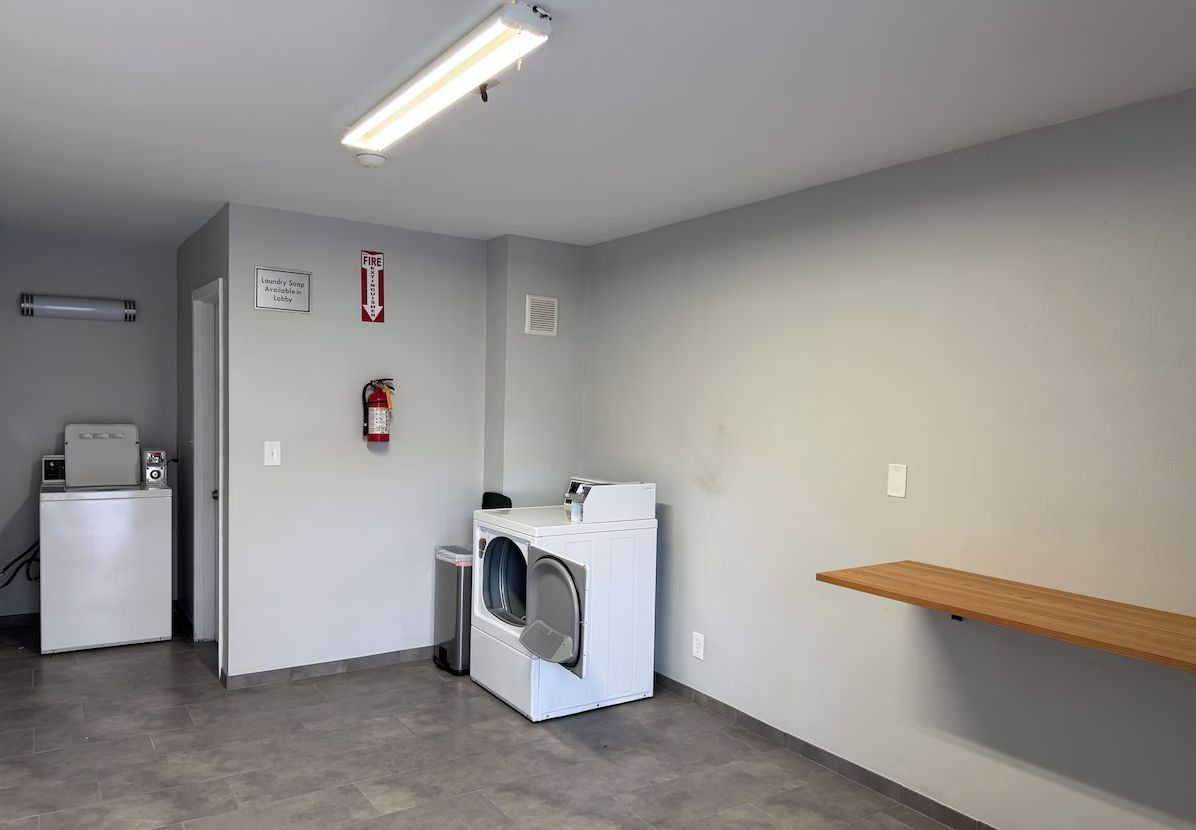 A laundry room with a washing machine, dryer, and a fire extinguisher on the wall.