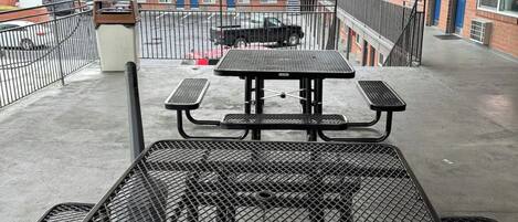 A rooftop patio with a picnic table and a metal grill.