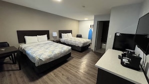 Ein Hotelzimmer mit zwei Betten, einem Schreibtisch, einem Fernseher und einer Küchenzeile.