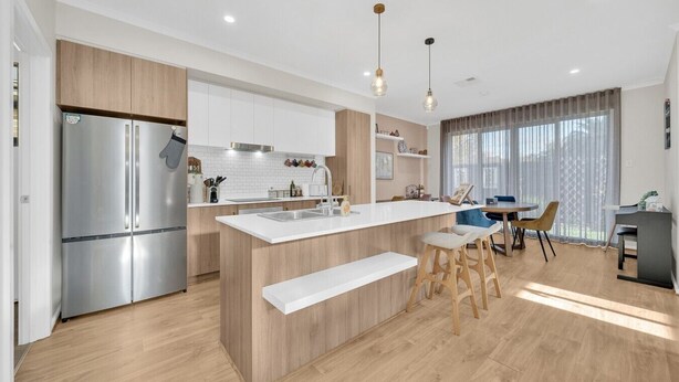 Une cuisine moderne dotée d’un îlot central, d’appareils électroménagers en acier inoxydable et de meubles de rangement en bois.