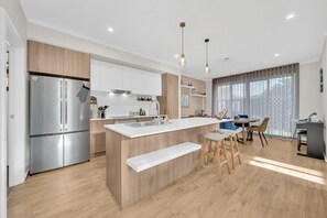 A modern kitchen with a central island, stainless steel appliances, and wooden cabinetry.