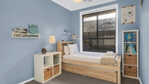 Une chambre à coucher avec un lit, une fenêtre, une étagère remplie de livres et un globe terrestre.