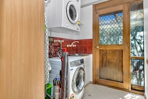 Une buanderie équipée d’un lave-linge, d’un sèche-linge et d’une porte en bois.