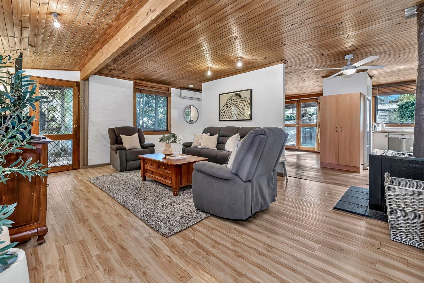 Un salon spacieux doté d’un plafond en bois, d’un ensemble de canapés, d’une table basse et d’une grande fenêtre offrant une vue sur l’extérieur.