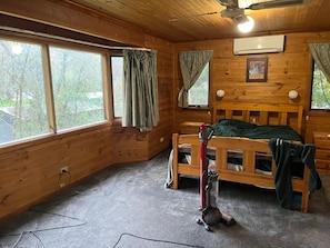 A wooden cabin room with bunk beds, a ceiling fan, and large windows. - Adelaide Hills Creek-Side Retreat (Bridgewater)