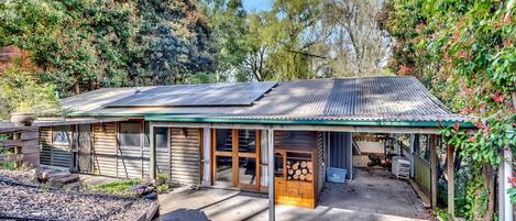A rustic cabin with a metal roof, wooden walls, and a covered porch area.
