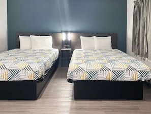 Ein Hotelzimmer mit zwei Betten, einem Nachttisch und einer Wandlampe.