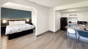 Ein modernes Hotelzimmer mit Bett, Schreibtisch, Stuhl, einer Küchenzeile und einem Badezimmer.