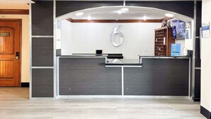 A reception desk with a digital screen, a large number '6' sign, and a security camera above. - Enjoy Affordable Comfort | 2 Units in Central Irving | Pet-Friendly Stay (Irving)