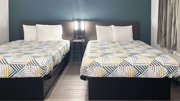 A hotel room with two beds, a nightstand, and a wall-mounted lamp. - 3 Units | Peaceful Irving Hideaway Perfect for Budget-Friendly Stays (Irving)