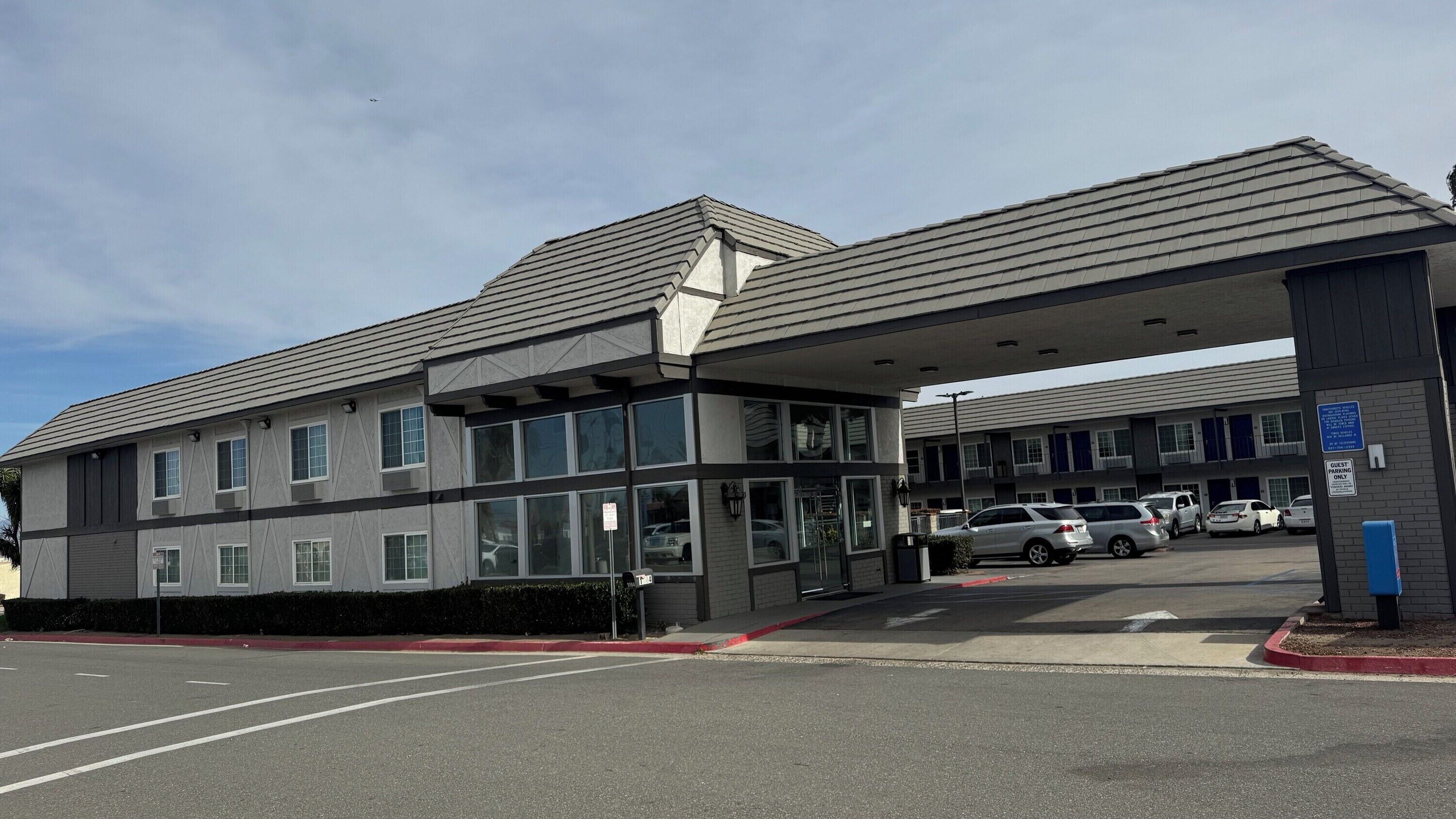 A multi-story hotel with a covered parking area and a clear sky.