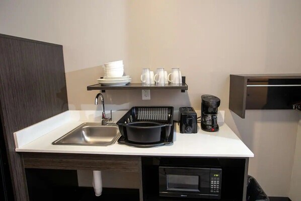 A compact kitchenette with a sink, a microwave, a toaster, and a coffee maker.