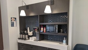 A modern kitchen with a microwave, coffee maker, and storage cabinets.