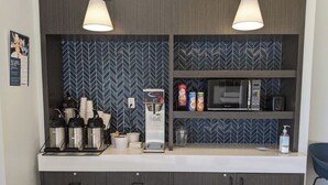A kitchenette with a microwave, coffee maker, and storage cabinets.