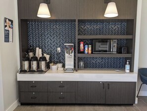 A kitchenette with a microwave, coffee maker, and storage cabinets.