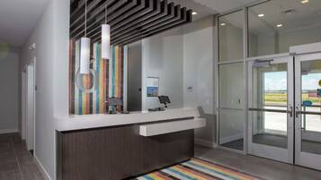 A reception area with a modern design, including a counter, a glass door entrance, and a striped rug.