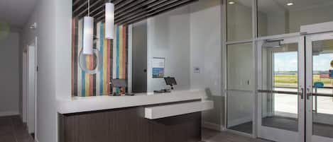 A reception area with a modern design, including a counter, a glass door entrance, and a striped rug.