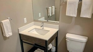 A bathroom with a sink, mirror, toilet, and towel rack.