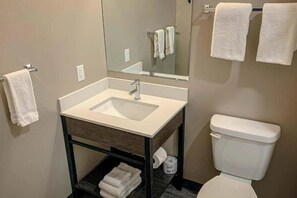 Un bagno con lavandino, specchio, WC e portasciugamani.