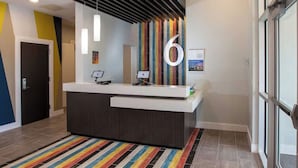 A reception desk with a modern design, a large number '6' on the wall, and a striped carpet.