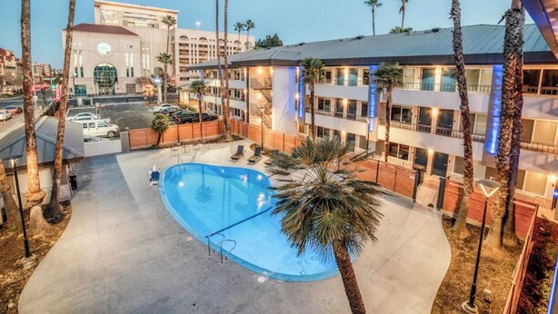 Ein Hotel mit Schwimmbad, Palmen und Blick auf die Stadt.