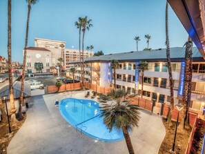 Ein Hotel mit Schwimmbad, Palmen und Blick auf die Stadt.