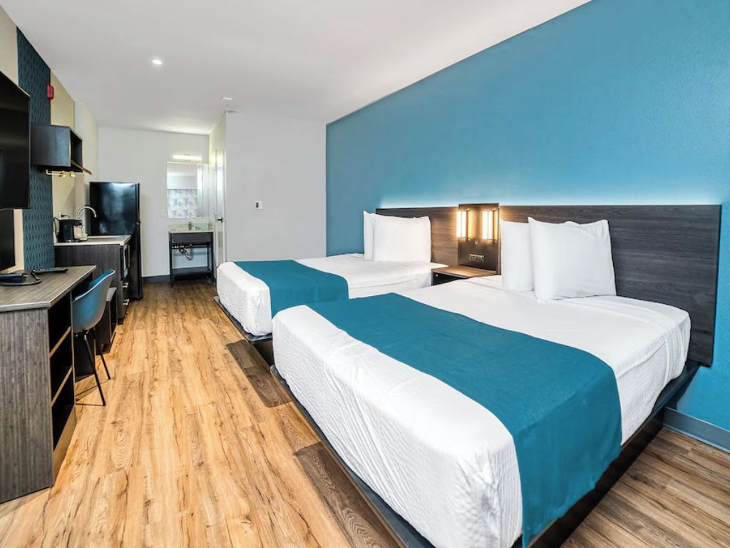 Habitación de hotel con dos camas, un escritorio y kitchenette.