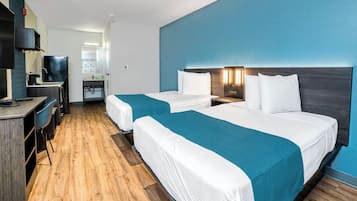 Habitación de hotel con dos camas, un escritorio y kitchenette.