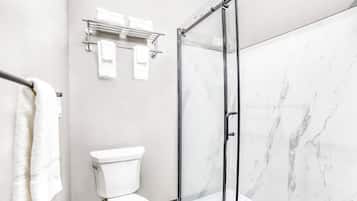 Et badeværelse med toilet, glasbrusekabine og en væg i marmor.