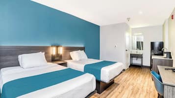 Una habitación de hotel con dos camas, un escritorio, una silla y un televisor.