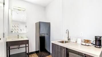 A compact kitchen with a refrigerator, a sink, a microwave, and a coffee maker.