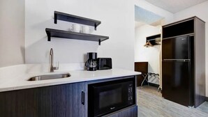 A modern kitchen with a sink, microwave, coffee maker, and black cabinets.