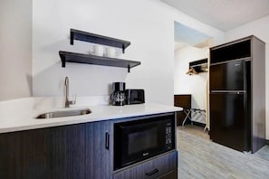 A modern kitchen with a sink, microwave, coffee maker, and black cabinets.