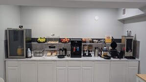 A kitchenette with a coffee machine, toaster, blender, and a refrigerator.