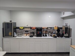 A kitchenette with a coffee machine, toaster, blender, and a refrigerator.