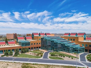 A modern building with multiple red-roofed sections, a central glass structure, and a landscaped courtyard. - 3 Convenient Rooms Great for Groups & Family Stays | Free Onsite Parking (Rock Springs)