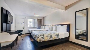 Ein Hotelzimmer mit Bett, Schreibtisch, Sessel, Fernseher und einem großen Spiegel.