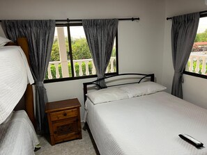 Ein Schlafzimmer mit zwei Betten, einem Nachttisch und einem Fenster mit Vorhängen.