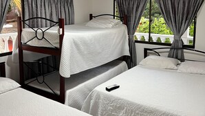 Una habitación con literas, una mesa y una ventana con cortinas.