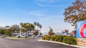 A parking lot with cars, a motel sign, and buildings in the background.