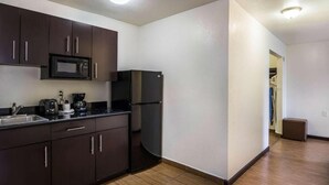 A compact kitchen with dark cabinets, a microwave, a refrigerator, and a coffee maker.