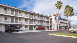 A motel with a two-story structure, a parking lot, and a few vehicles.